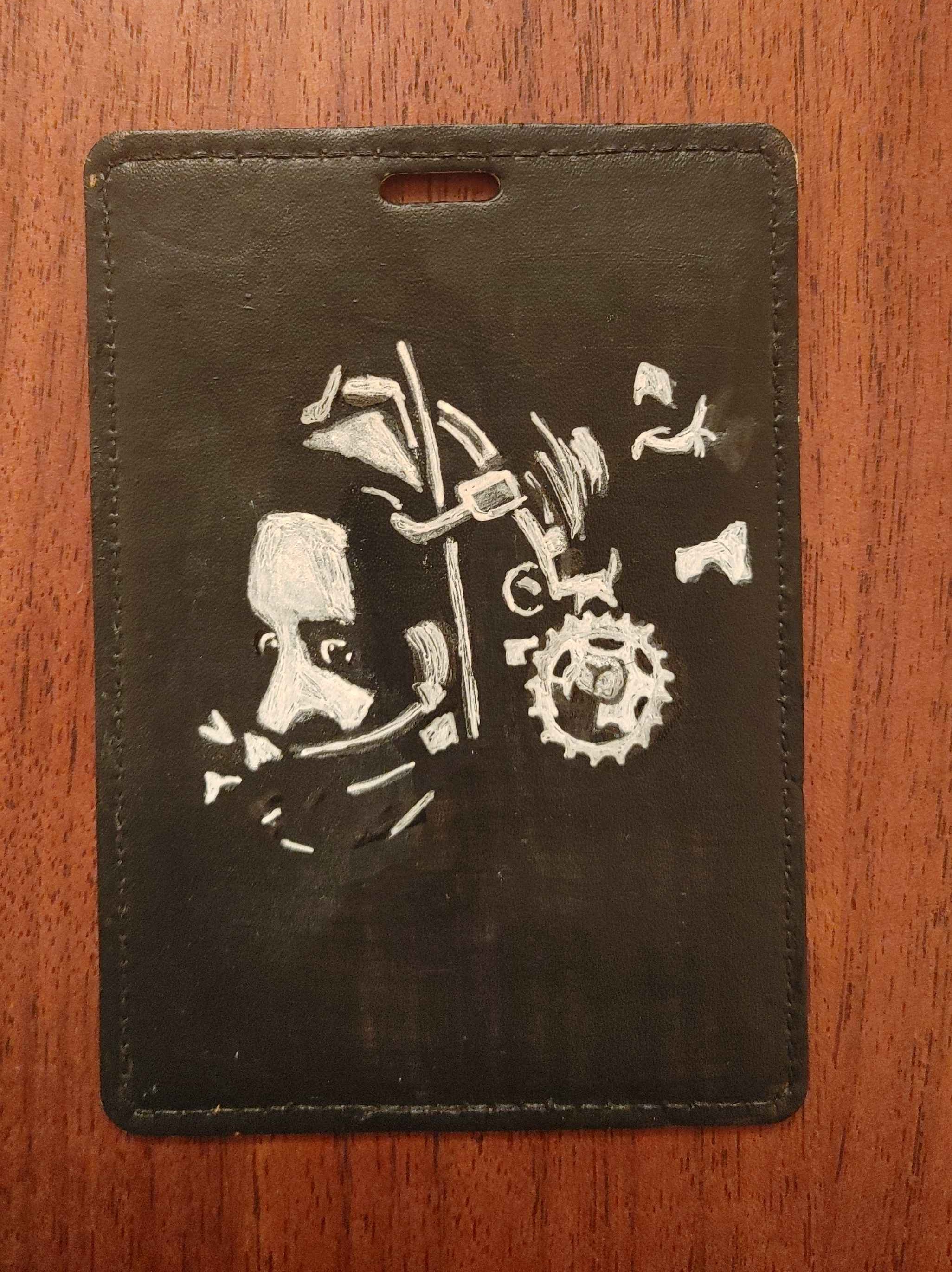 An id holder with a portrait of Amanda Young from Saw painted on it in black and white. She is wearing the reverse bear trap.