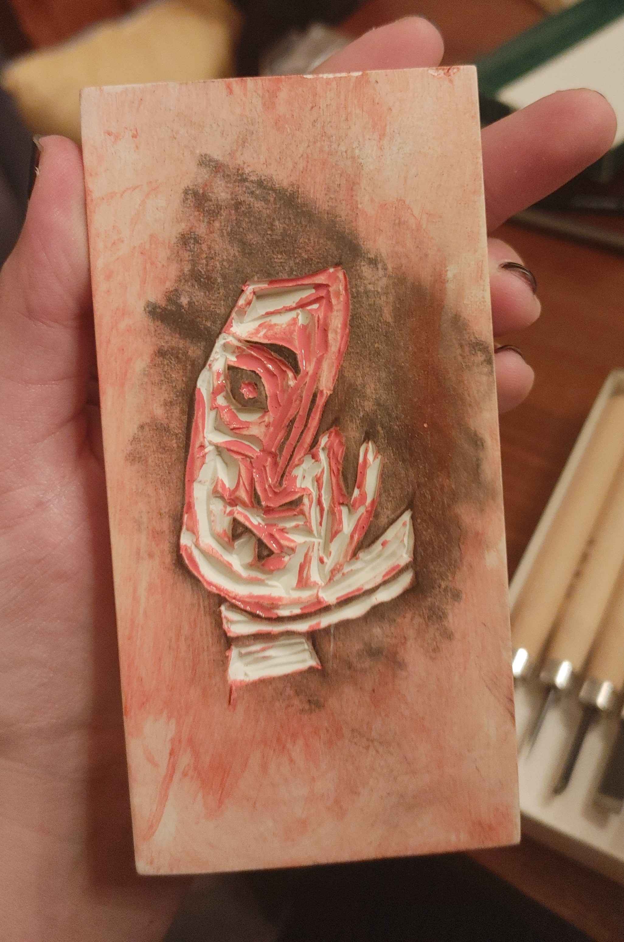 A rubber block with the mirrored sketch of Matty carved into it. The block is covered in paint and graphite.